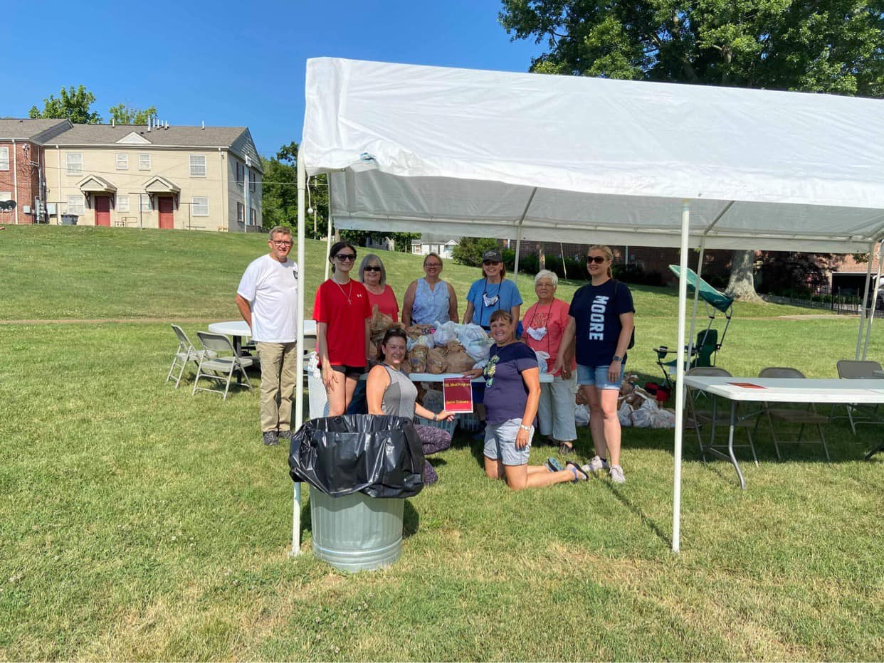 Community members gathered under a canopy at an outdoor event