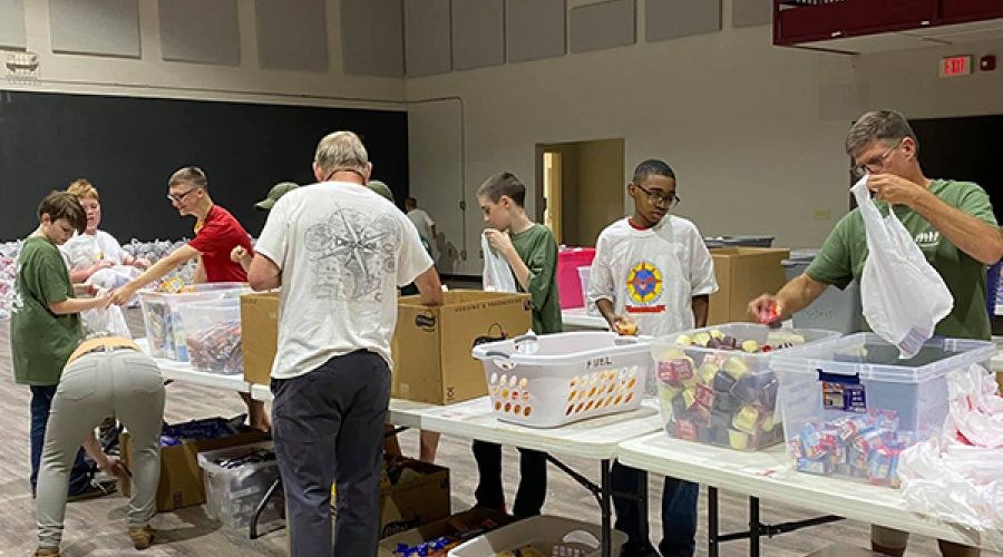 Community volunteers packing bags of food around tables